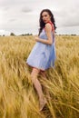 Woman in a blue light dress stands in a field Royalty Free Stock Photo