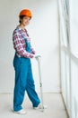 Woman in blue overalls as construction worker hold level standing near windows. concept of women`s work in men`s professions and Royalty Free Stock Photo
