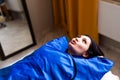 Woman in blue pressotherapy suit lying down having pressure therapy for weight loss in spa salon. Doctor help lose weight and