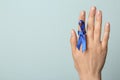 Woman with blue ribbon on against light background, closeup. Symbol of social and medical issues