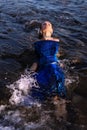 A woman in a blue shiny dress lies in the water Royalty Free Stock Photo