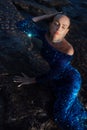A woman in a blue shiny dress lies in the water Royalty Free Stock Photo