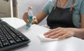 Woman in blue shirt and apron using rubbing alcohol spraying and on working table