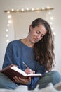 Woman in blue sweater making notes in her journal