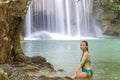 Woman in blue swimsuit relax in water at Erawan Waterfall