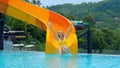 Woman in blue swimwear slides down a water slide at an aquapark resort Royalty Free Stock Photo