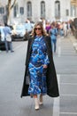 Woman with blue tones dress and long black coat before Giorgio Armani fashion show, Milan