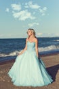 Woman in blue tulle dress enjoying sun on beach