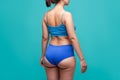 Woman in blue underwear on turquoise background