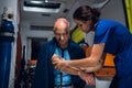 Woman in blue uniform wraps a tourniquet around a hand of injured man