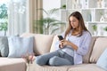 Woman in blue using phone on a couch at home Royalty Free Stock Photo