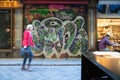 Woman blurred in motion walking past closed roller door of business