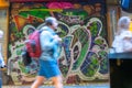 Woman blurred in motion walking past closed roller door of business