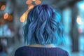 Woman with bob hairstyle with wavy blue hair on blurred background close-up, rear view.