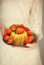 Woman, boho bride holding little cake on a plate with strawberries