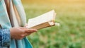 Woman with book over nature background. Time for reading. Hipster young girl on a walk in spring. Free space for your mock up Royalty Free Stock Photo