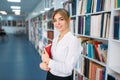 Woman with book poses at the shelf in library Royalty Free Stock Photo