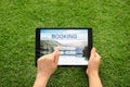 Woman booking tickets online on green grass, closeup. Travel agency concept