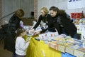 Woman bookseller selling little girl and her mother book, bookstore. Book Fair. Kyiv, Ukraine Royalty Free Stock Photo