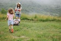 A woman in boots with her child in the form of a game mows the grass with a lawnmower in the garden Royalty Free Stock Photo