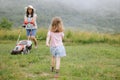 A woman in boots with her child in the form of a game mows the grass with a lawnmower in the garden Royalty Free Stock Photo