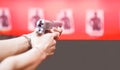 Woman Both Hands holding magnum gun, index finger on trigger, aiming ready to shoot on targets on red wall background. Sport,