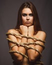 Woman bound rope prisoner in jeans gray background Royalty Free Stock Photo