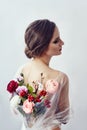 Woman with a bouquet of artificial flowers behind her. The girl in a light transparent dress with an open back and flowers. Art Royalty Free Stock Photo