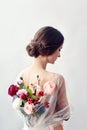 Woman with a bouquet of artificial flowers behind her. The girl in a light transparent dress with an open back and flowers. Art Royalty Free Stock Photo