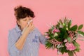 Woman bouquet of flowers hands take hankie sneezes closed eyes concept allergy illness discomfort pink background