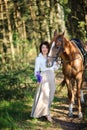 Woman with a bouquet of flowers walks with the favourite horse