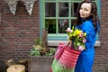 Woman with a bouquet of fresh tulips yellow and pink in the hands. With corset for shopping. On the street of the old European