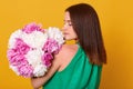 Woman with bouquet of pink and white peonies in hands, posing backwards, girl in light transparent dress. Dark haired lady holding Royalty Free Stock Photo