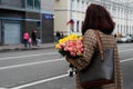 Woman with bouquet of pink and yellow roses in city