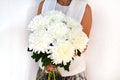 Woman with bouquet of white chrysanthemums. Beautiful fresh white flowers for holiday. Woman holding beautiful white flowers