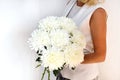 Woman with bouquet of white chrysanthemums. Beautiful fresh white flowers for holiday. Woman holding beautiful white flowers