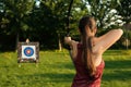 Woman with bow and arrow aiming at archery target in park, back view Royalty Free Stock Photo
