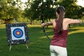 Woman with bow and arrow aiming at archery target in park, back view Royalty Free Stock Photo