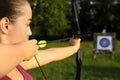 Woman with bow and arrow aiming at archery target in park, closeup Royalty Free Stock Photo