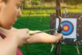 Woman with bow and arrow aiming at archery target in park Royalty Free Stock Photo