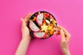 Woman with bowl of delicious exotic fruit salad on pink background, top view Royalty Free Stock Photo