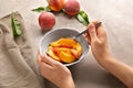 Woman with bowl full of sliced peaches at light table Royalty Free Stock Photo