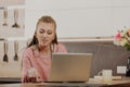 Woman with box-braids multitasks with phone, laptop, kitchen