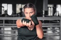 Woman boxer getting ready to fight. Horizontal shot of stylish young woman boxer wearing handwraps training indoors