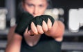 Woman boxer getting ready to fight. Horizontal shot of stylish young woman boxer wearing handwraps training indoors