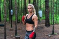 Woman boxer professional fighter posing in boxing stance, working out outdoors Royalty Free Stock Photo