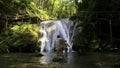 Woman and boy child bathing in beautiful waterfall in dense jungles. Creative. Woman and a boy in cold mountainous river Royalty Free Stock Photo