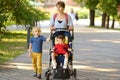 Woman with a boy and a disabled girl in wheelchair walking in park summer. On baby legs orthosis. Child cerebral palsy. Treatment