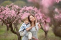 Woman and boy are standing by flowering bush of lilac. She smells flowers. Family time together. Royalty Free Stock Photo