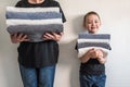 Woman and a boy standing near walls, holding stacks of different towels. Family concept Royalty Free Stock Photo